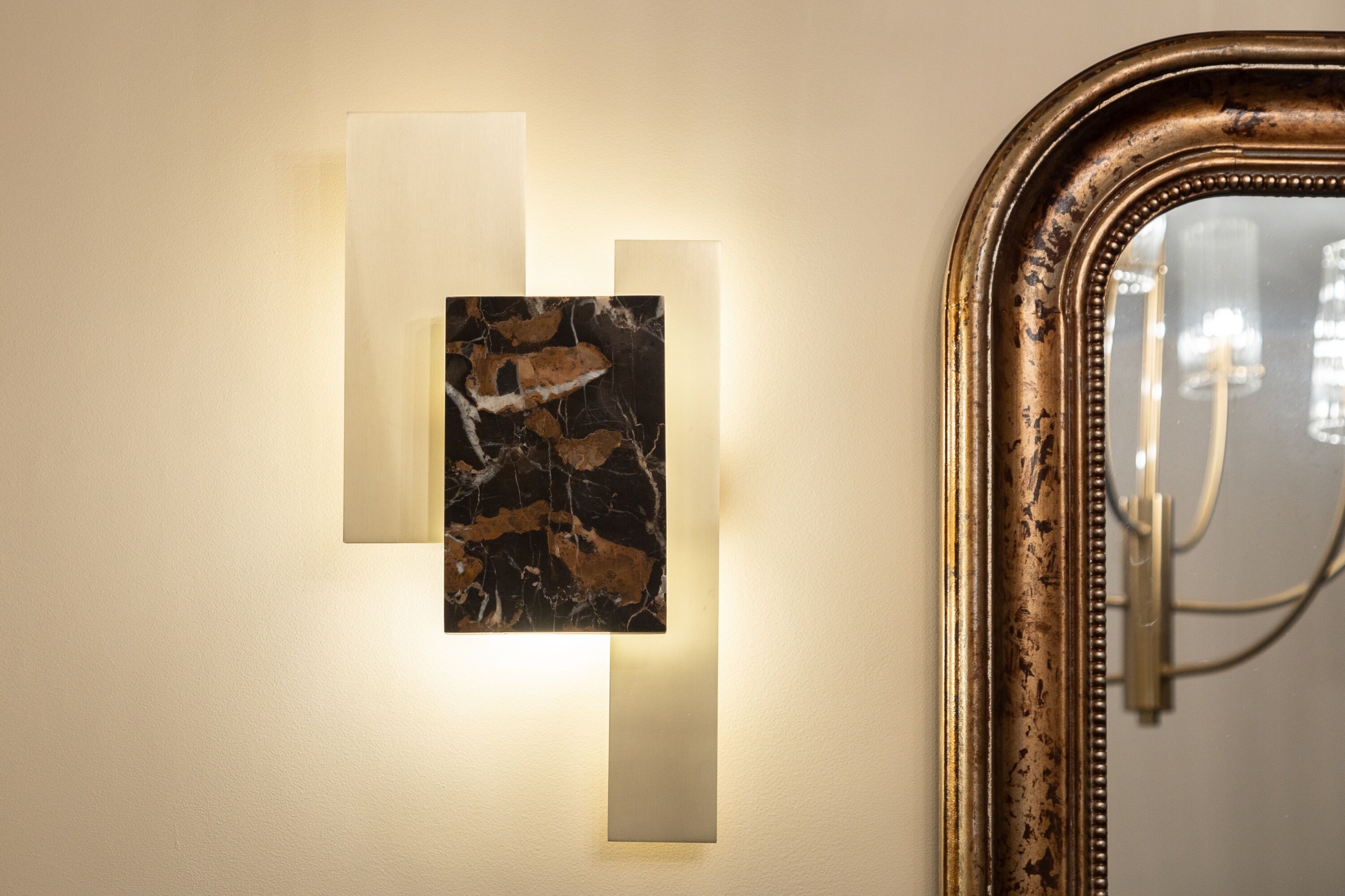 A wall with a framed mirror and two rectangular light panels.