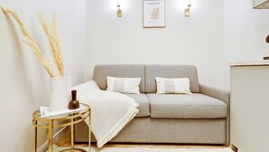 A neutral-toned room with a sofa, a small side table, and two wall-mounted lights. - Maison Belleville (Paris)