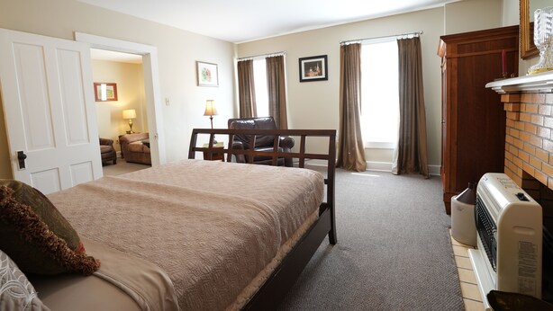 A bedroom with a bed, a desk, a chair, a radiator, and a fireplace.