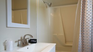 A bathroom with a sink, mirror, and shower.