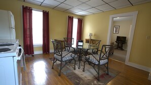 A dining area with a table and chairs, a refrigerator, and a window with curtains.
