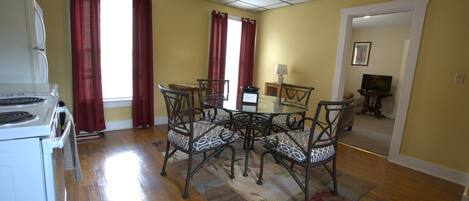 A dining area with a table and chairs, a refrigerator, and a window with curtains.