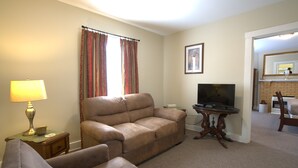 A living room with a sofa, a television, a lamp, and a small table.