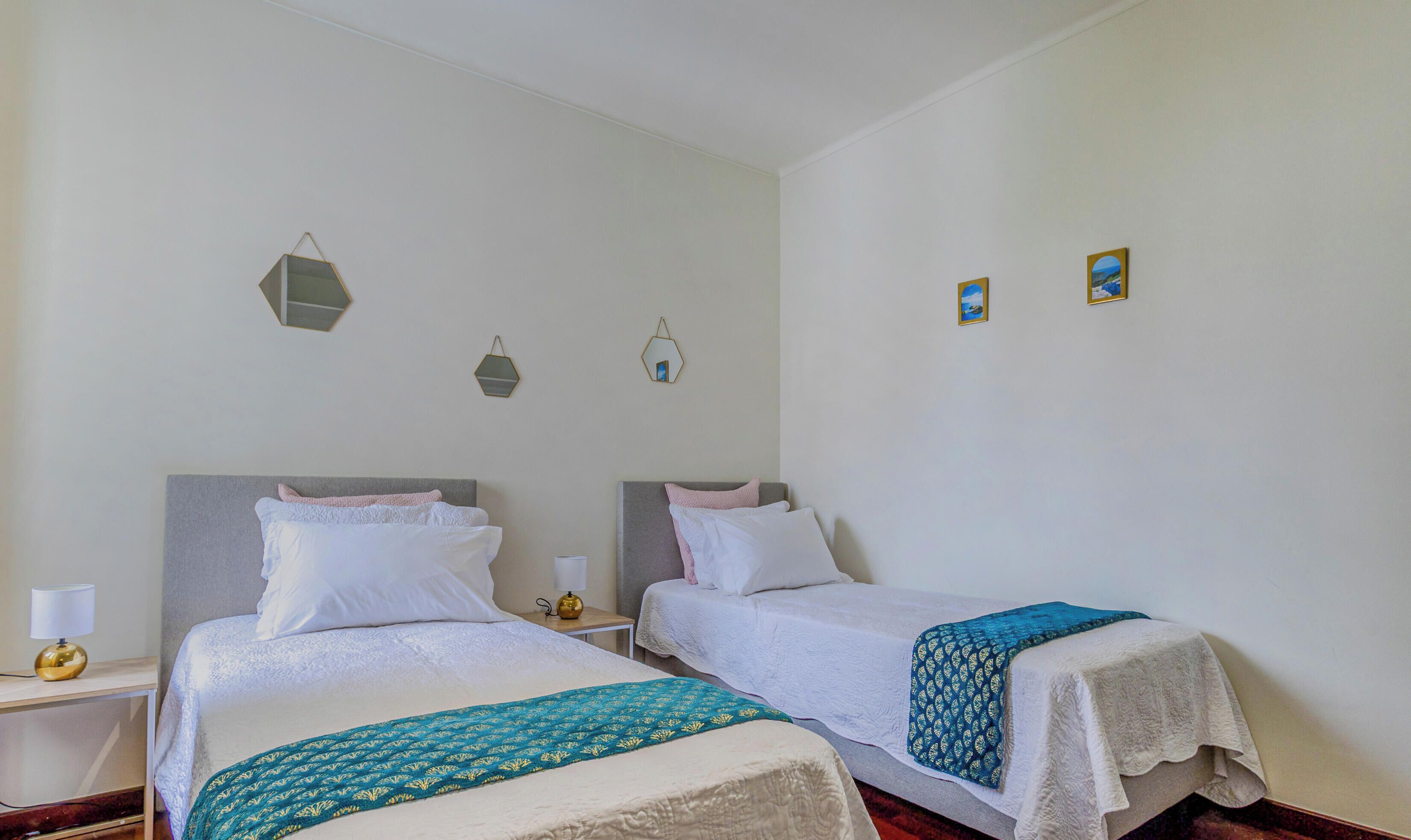 A twin room with two beds, a bedside table with a lamp, and wall-mounted light fixtures.