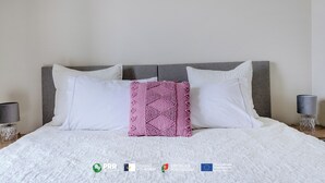 A neatly made bed with white bedding and a single decorative pillow.