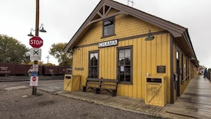A yellow wooden building labeled 'CHAMA' with a bench outside, a stop sign, and a 'NO PARKING' sign.