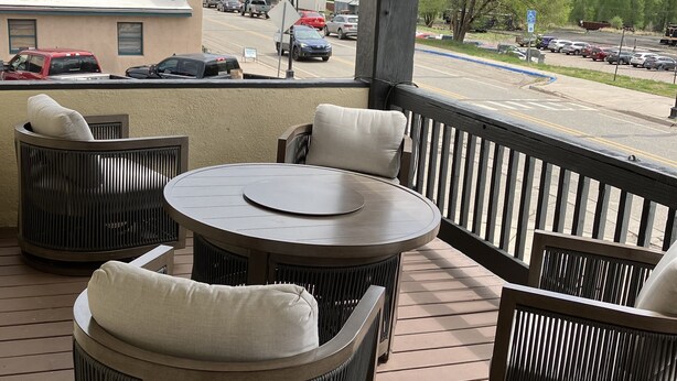 A covered outdoor seating area with wicker furniture and a round table.