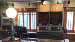 A wooden reception desk with a lamp, a laptop, and a telephone.