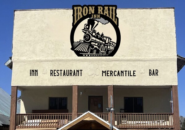 A building with a sign that reads "Iron Rail Inn Restaurant Mercantile Bar" and features a train graphic.