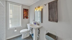 Ein Badezimmer mit Toilette, Waschbecken und großem Fenster mit Jalousien.