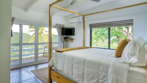 A bedroom with a bed, a ceiling fan, a TV, and a window with a view of greenery. - Amazing mountain top villa! (Castries)