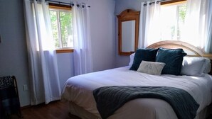 A bedroom with a wooden bed, white bedding, and a mirror above the bed.