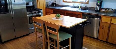 A kitchen with wooden cabinets, a stainless steel refrigerator, a stove, a sink, and a dishwasher.
