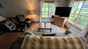 A cozy living room with a leather sofa, a wooden coffee table, and a television on a wooden cabinet.
