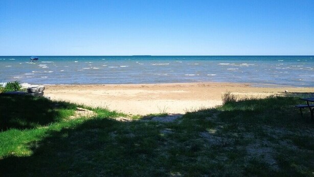 A beach with a clear sky, calm sea, and a sandy shore.