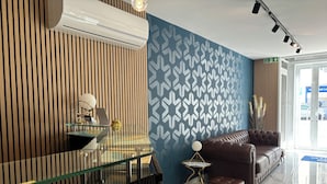 Una zona de recepción moderna con un escritorio de vidrio, un sofá de cuero marrón y una pared con diseño.