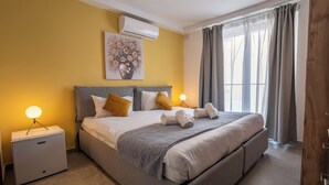 Una cama bien hecha con almohadas, una lámpara de noche y una mesita de noche con lámpara.