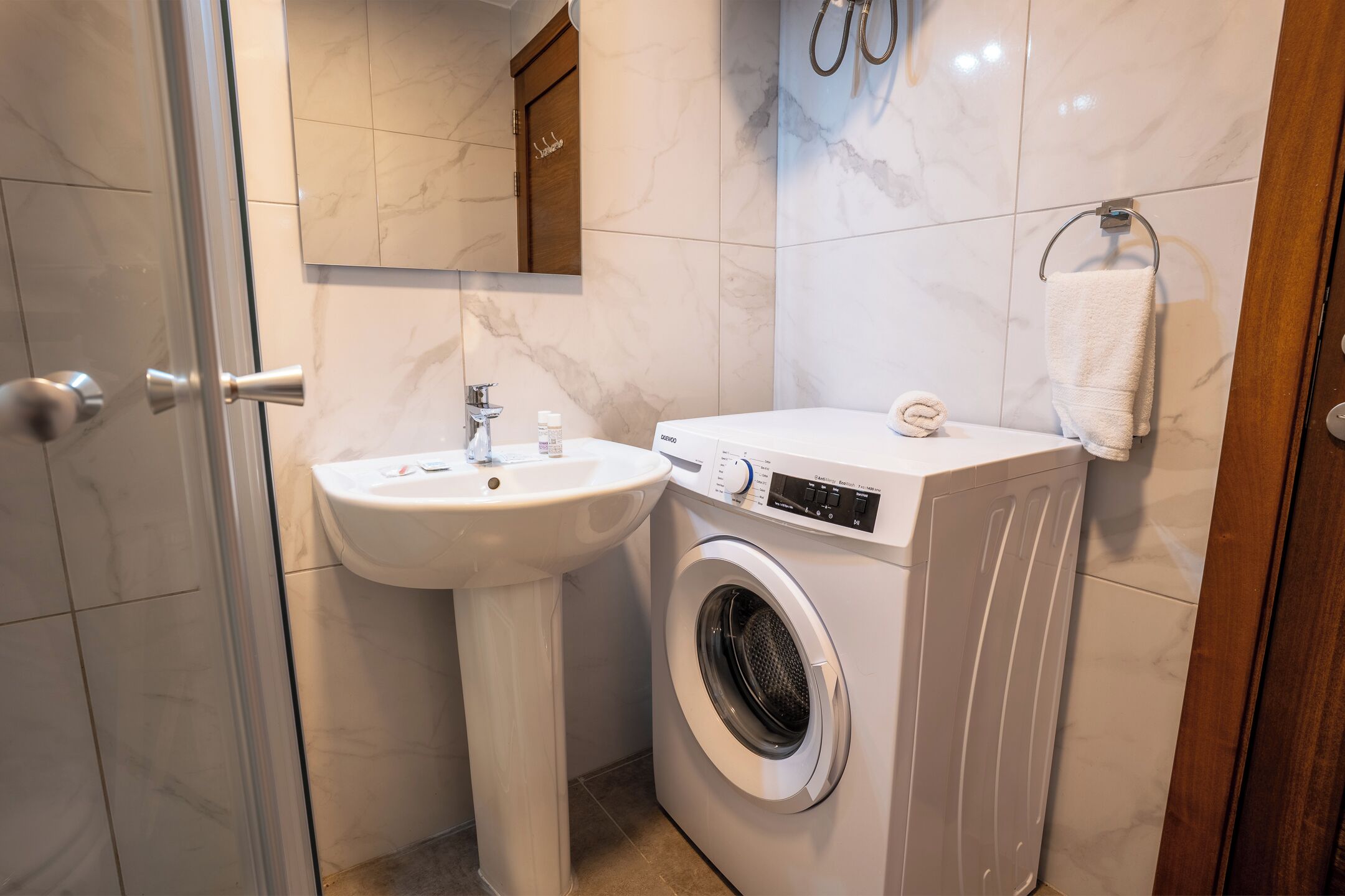 Une salle de bain équipée d’un lavabo, d’un lave-linge, d’un miroir et d’un porte-serviettes.
