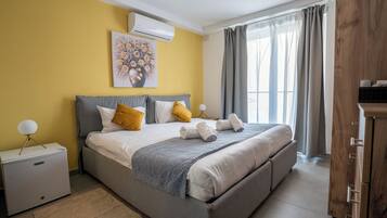 Un dormitorio con cama, mesitas de noche, aire acondicionado, una ventana con cortinas y un armario de madera.