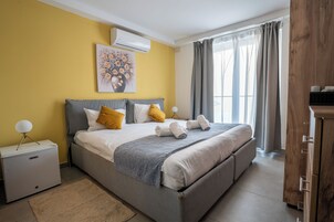 Un dormitorio con cama, mesitas de noche, aire acondicionado, una ventana con cortinas y un armario de madera.