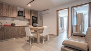 Una cocina moderna con armarios de madera, una mesa de comedor con sillas, un horno empotrado y un equipo de aire acondicionado.