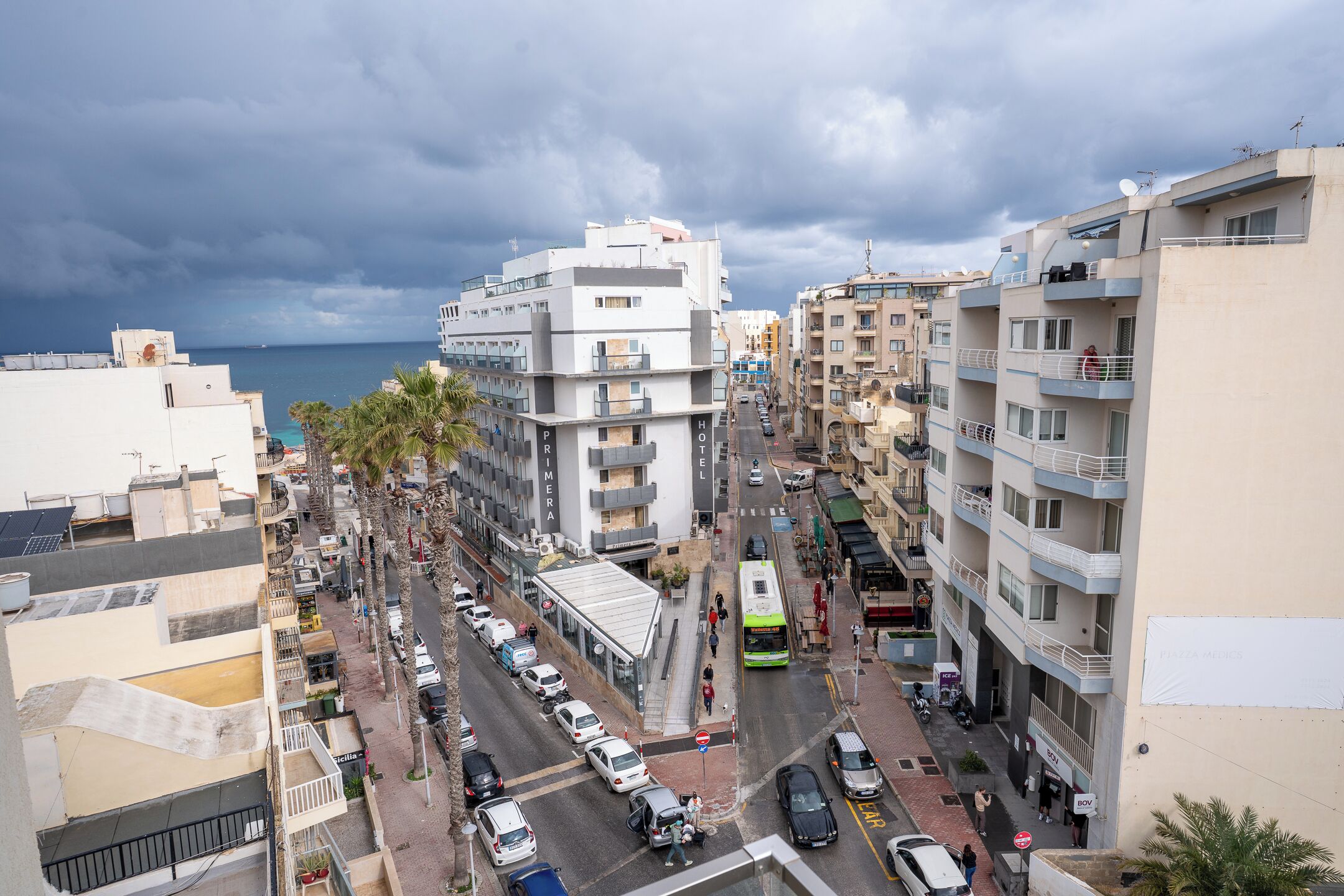 Panorama urbano con edificios, una calle y vista al mar.