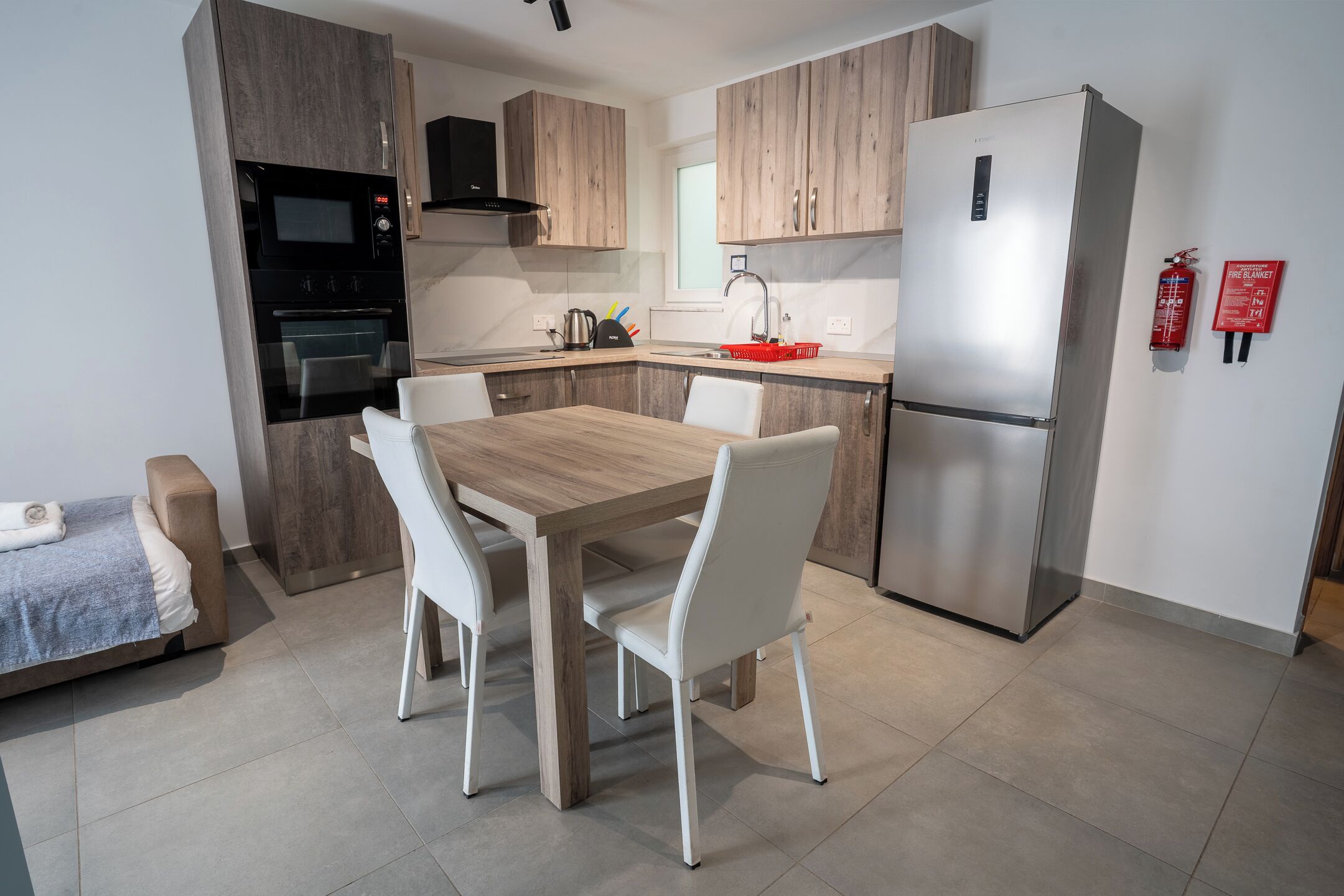 Una cocina moderna con una mesa de comedor, sillas, un refrigerador y un microondas.