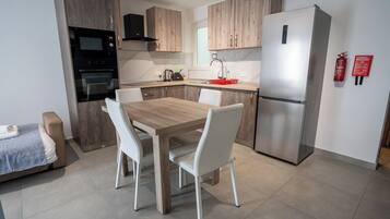 Una cocina moderna con una mesa de comedor, sillas, un refrigerador y un microondas.