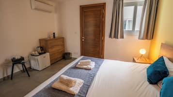 Una habitación de hotel con cama, cómoda, escritorio y ventana con cortinas.