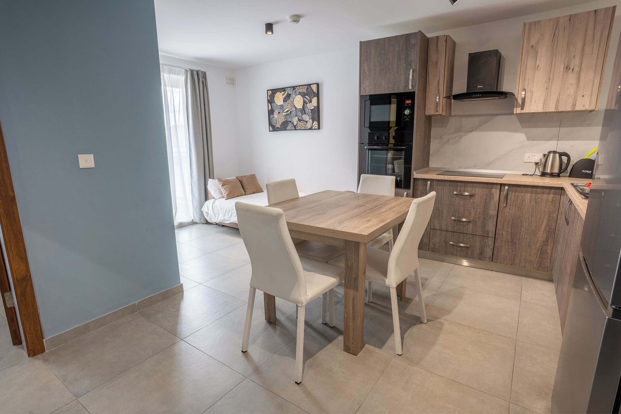 A modern kitchen with wooden cabinets, a dining table with chairs, and a built-in oven.
