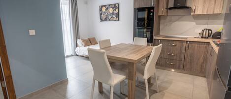 Una cocina moderna con armarios de madera, una mesa de comedor con sillas y un horno empotrado.