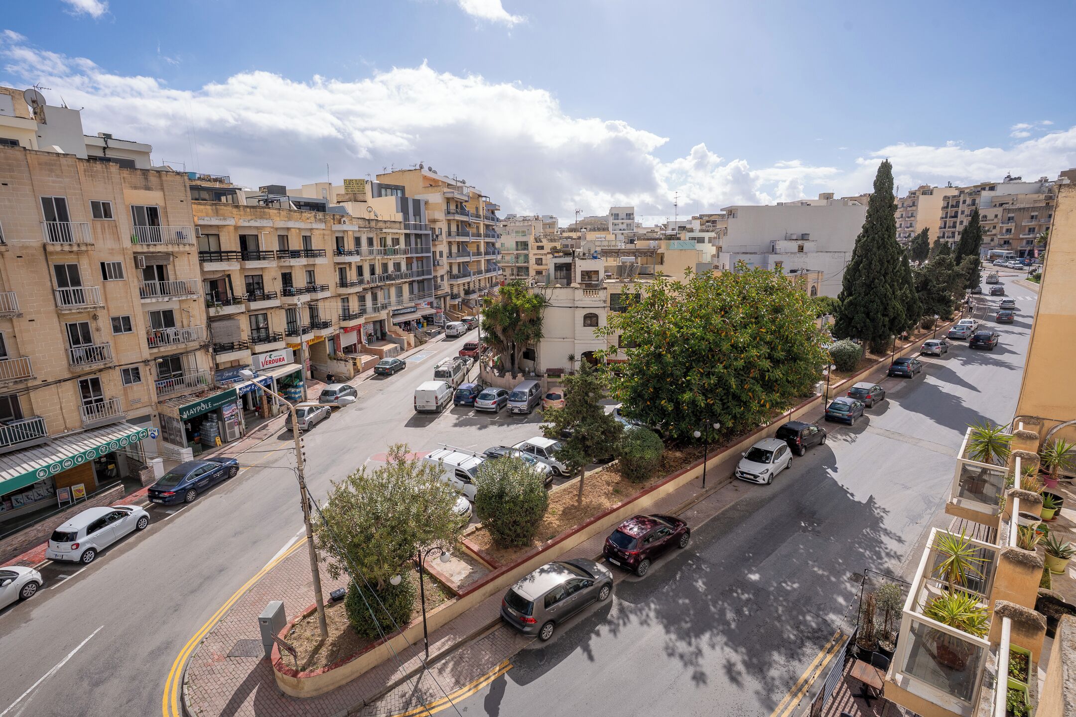 Un immeuble résidentiel à plusieurs étages, doté de balcons, d’un parking et donnant sur la rue.