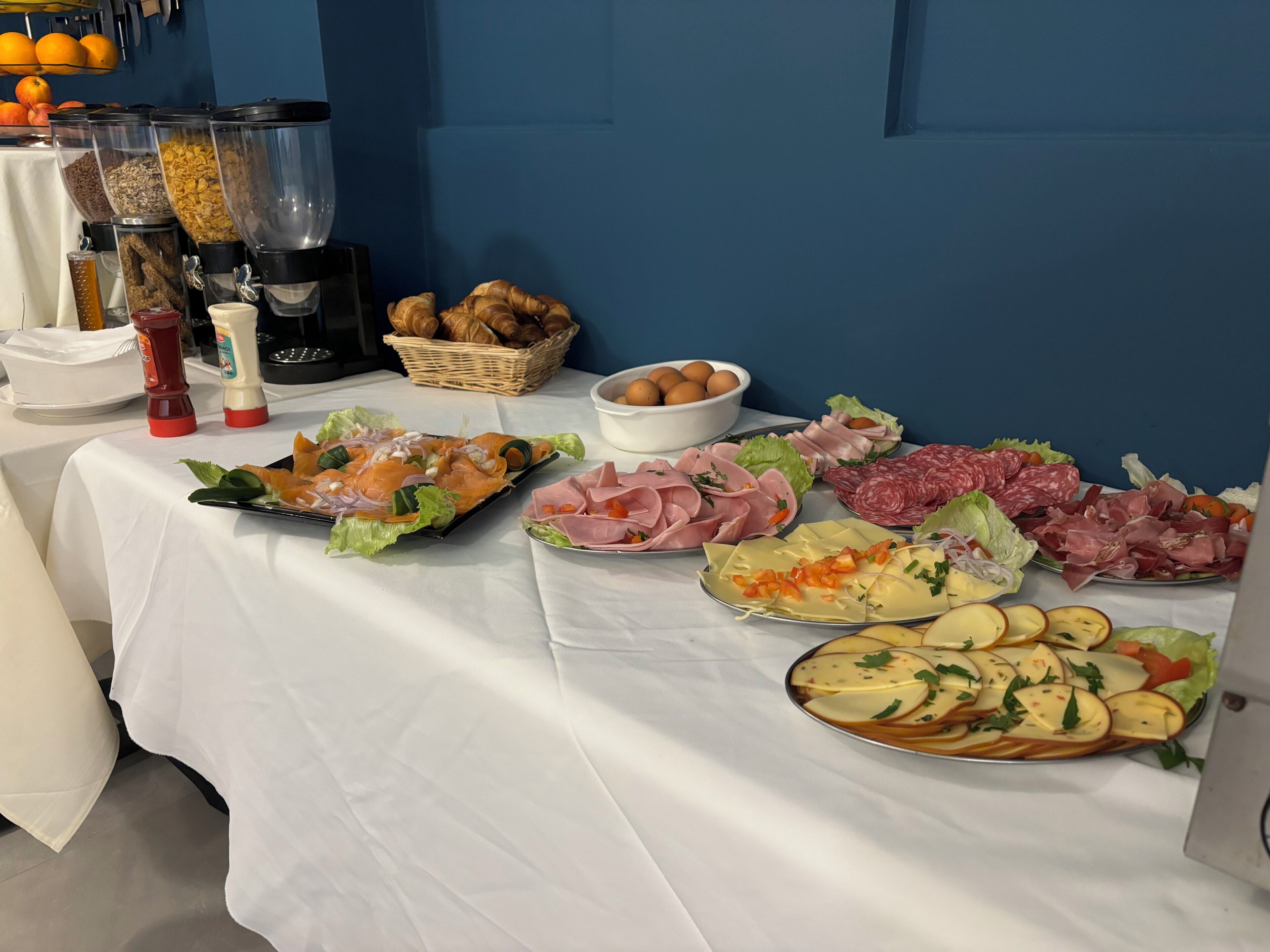 A buffet table with various food items including salads, meats, and bread.