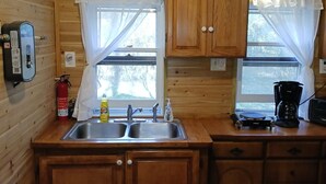 Una cucina compatta con pareti in legno, un lavello, pensili, un bollitore e una macchina per il caffè.