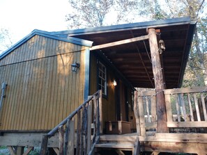 Een houten hutje met een veranda, een trap en een lantaarn.