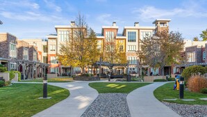 Un complexe résidentiel moderne doté d’une cour intérieure, de promenades pavées et de façades de bâtiments aux styles variés.