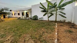 A white building with a small garden area, including a banana tree and a bench. - Sleep6-casa Blanca-privategarden-offstreet-kasoa (Kasoa)