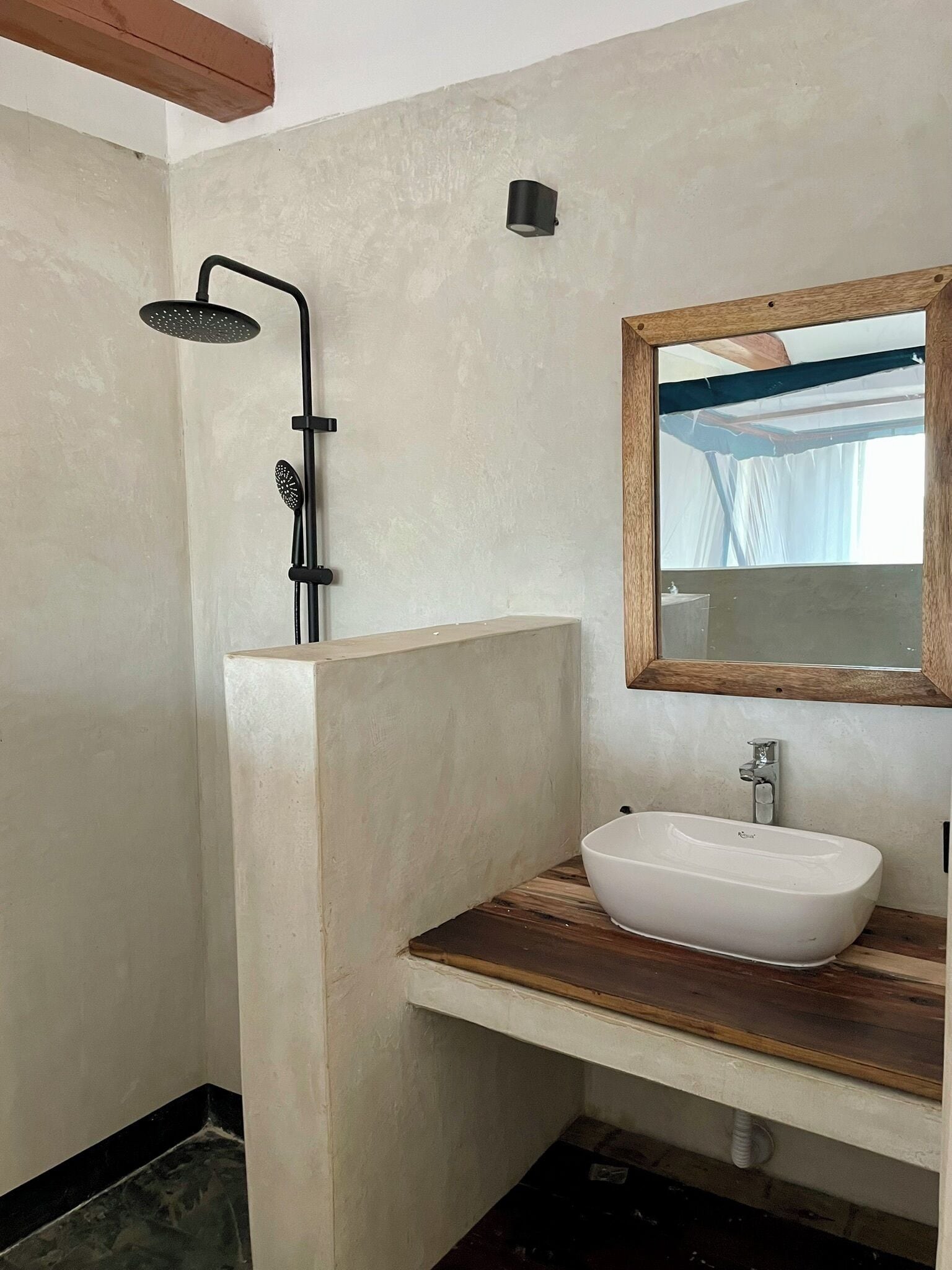 A bathroom with a freestanding bathtub, a wooden vanity, a wall-mounted mirror, and a showerhead.