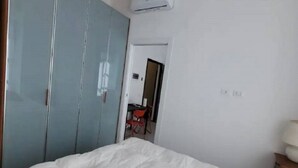 Une chambre à coucher avec un lit, un oreiller rouge, une armoire et un bureau avec une chaise.