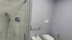 Une salle de bain avec une douche à parois de verre, un bidet et des toilettes.