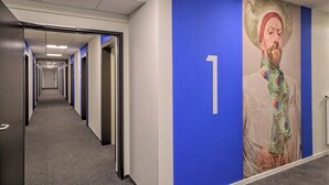 Un couloir avec un mur d’accent bleu, un panneau portant le chiffre « 1 » et un motif de plumes de paon sur le mur.