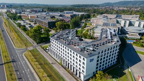 Un bâtiment moderne doté d’un toit plat, de nombreuses fenêtres et d’un parking.