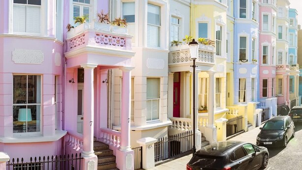 A row of colorful terraced houses with distinct pastel colors, white railings, and small balconies. - Colourful House 3 Bed Apt - Notting Hill (London)