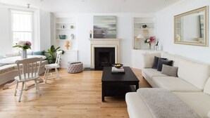Een moderne woonkamer met een open haard, een bank, een salontafel en een eethoek met stoelen en een tafel.