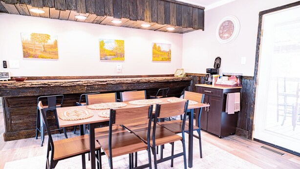 A dining area with a wooden table and chairs, a rustic wooden counter, and wall-mounted artwork. - Charming & Rustic 4-bedroom Home with Hot Tub, Golf Cart, and large yard! (Dandridge)