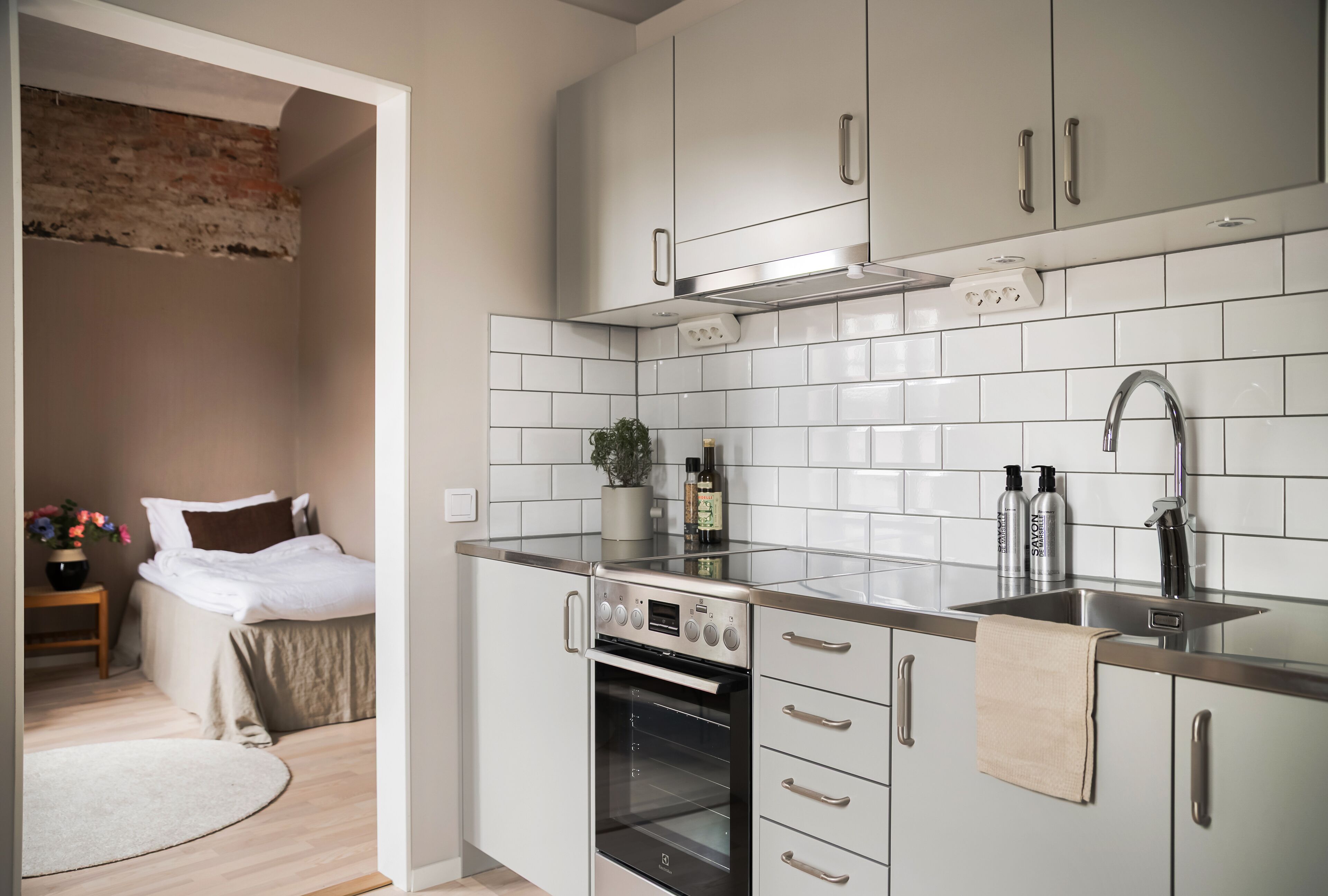 A compact kitchen with white cabinets, a stainless steel sink, and a built-in oven.