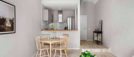 A modern living room with a dining area, a kitchen in the background, and a staircase leading to another level.