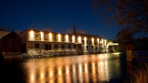A large, illuminated building with multiple windows and a stone foundation, reflecting on a wet surface. - Mörrum River  (Mörrum)