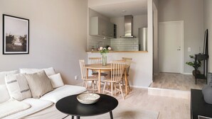 A modern living room with a sofa, a dining table with chairs, a black coffee table, and a kitchen area in the background. - Mörrum River  (Mörrum)