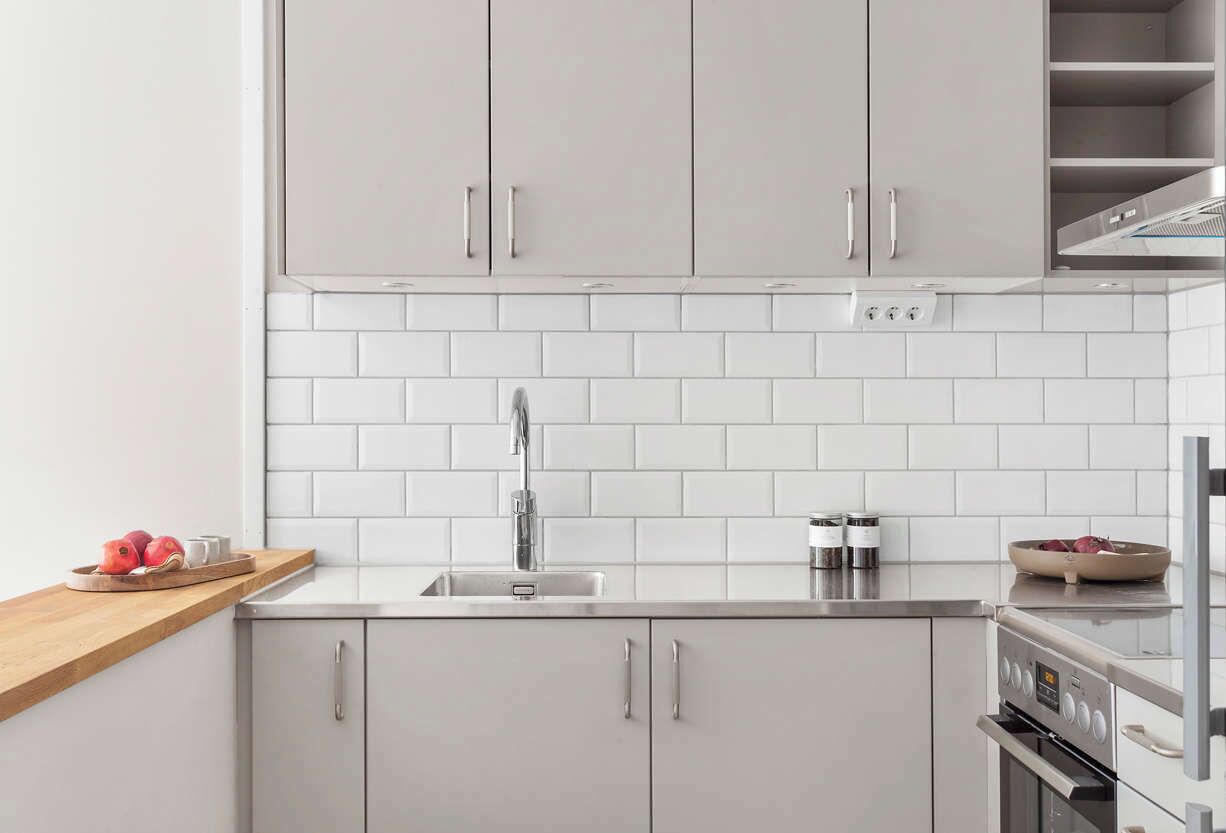 A modern kitchen with white cabinets, a stainless steel sink, and a built-in oven.